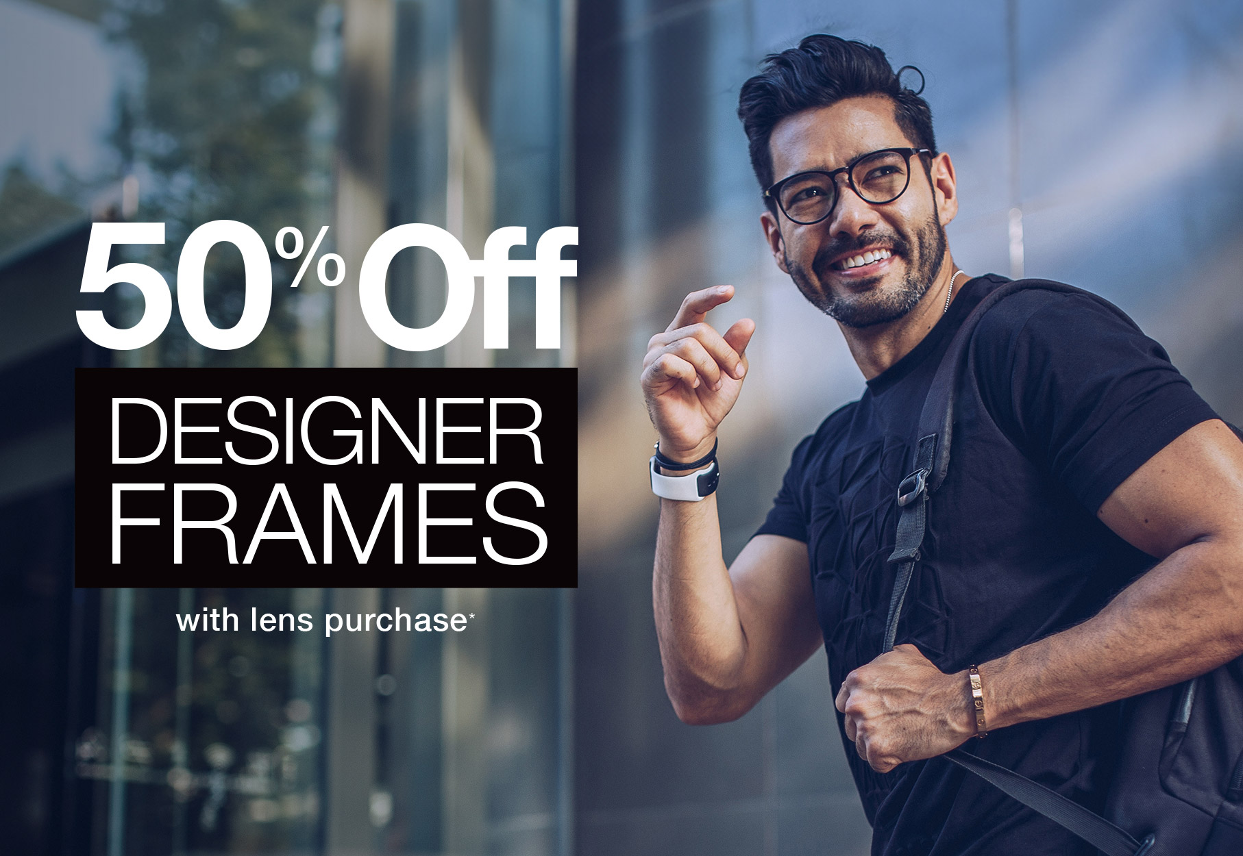 Text: 50% off designer frames with lens purchase* Photo: smiling man wearing eyeglasses and a black t-shirt with a backpack over his shoulder
