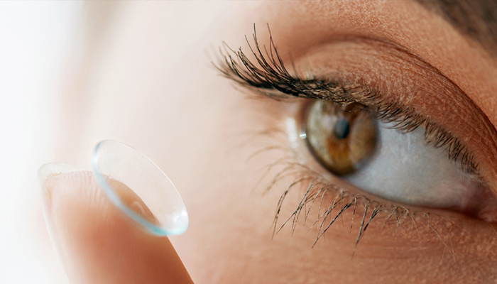 a closeup of a person putting a contact lens in their eye