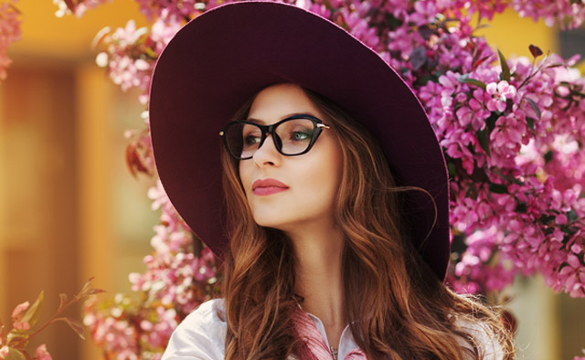 A woman wearing a hat and glasses standing outdoors