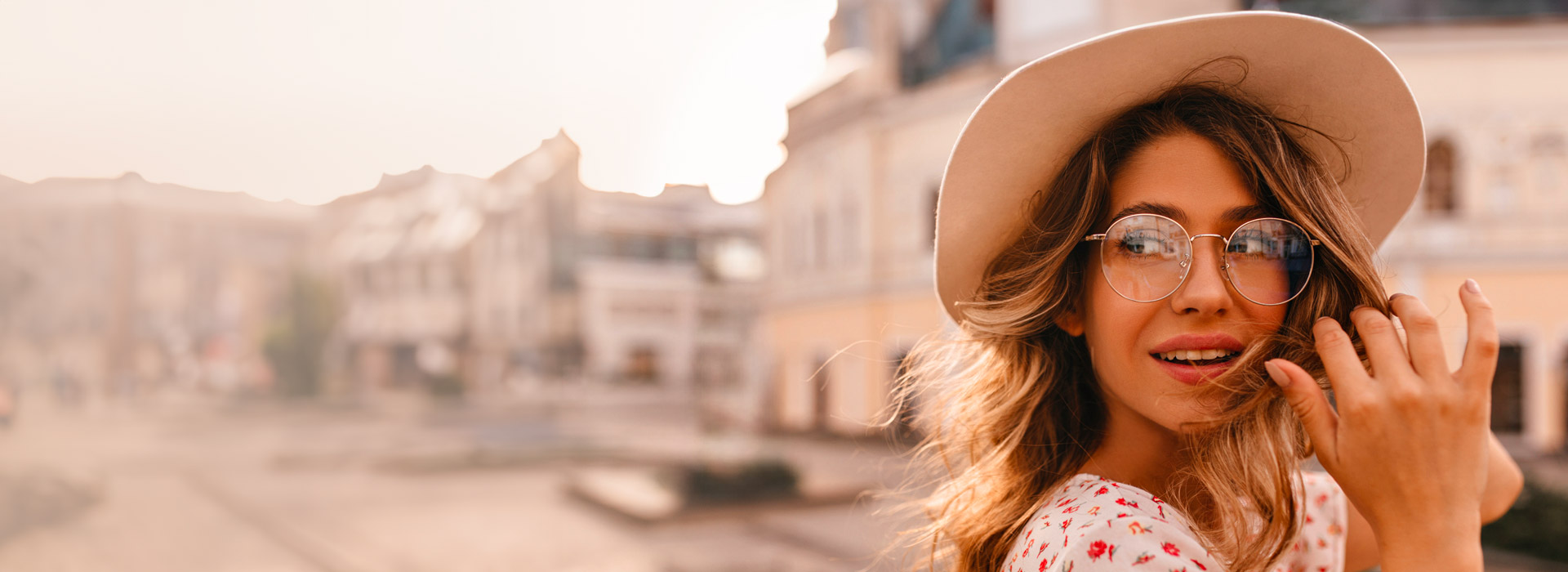 Photo: girl wearing a hat and eyeglasses with a city in the background