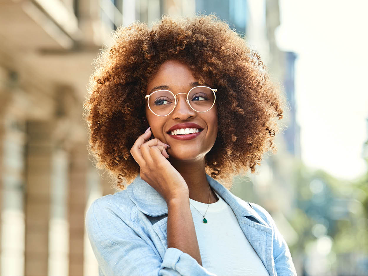 Smiling woman wearing eyeglasses and holding a cell phone to her ear.