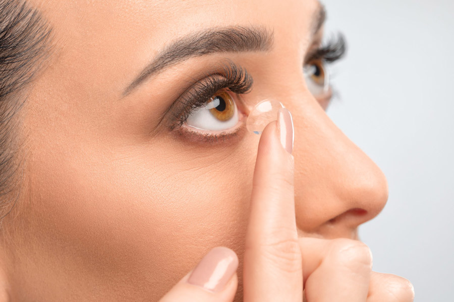 closeup of woman putting a contact lens in her right eye